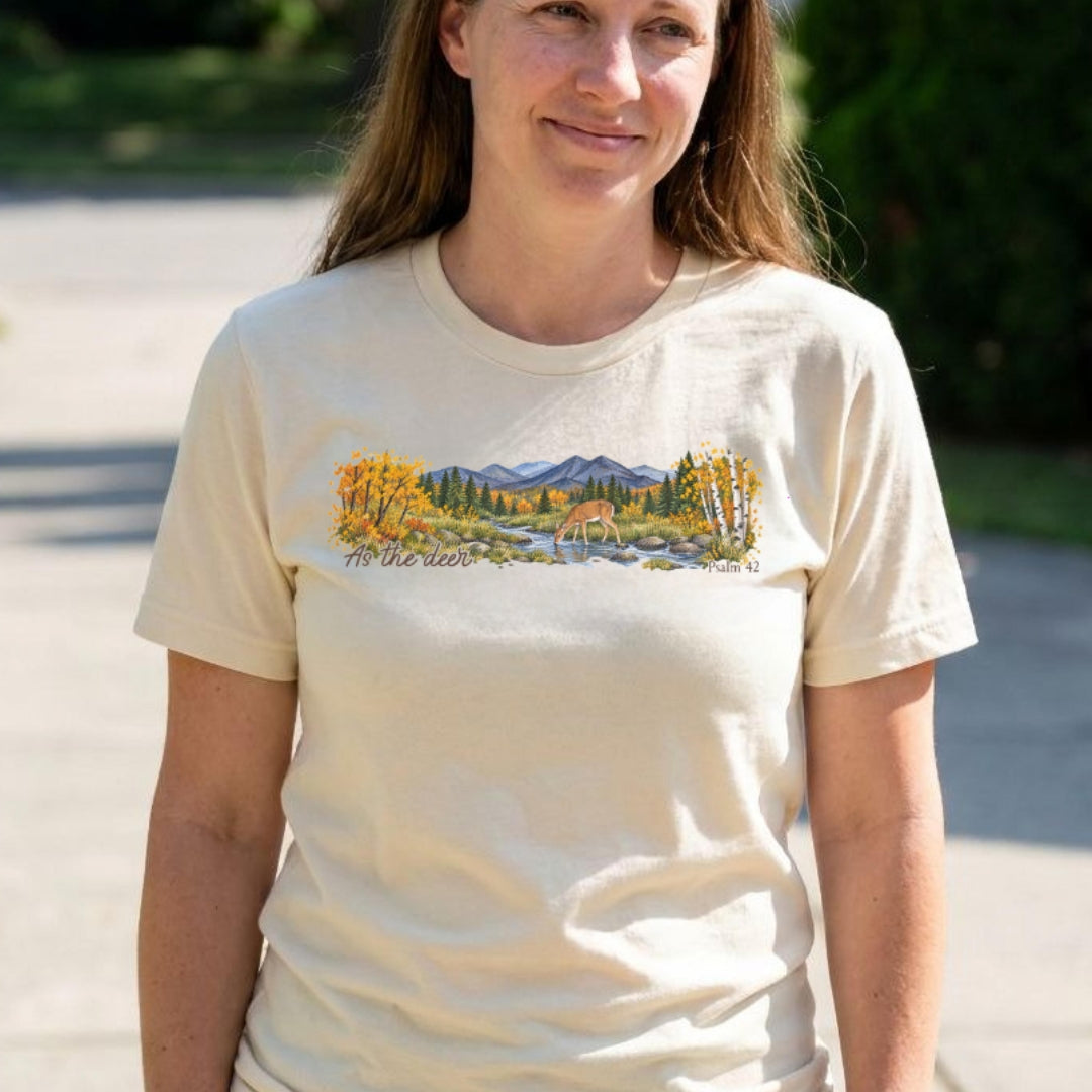 shirt with a wide watercolor style mountain landscape, golden trees, a deer drinking from a rocky creek, and “As the deer” and “Psalm 42.”
