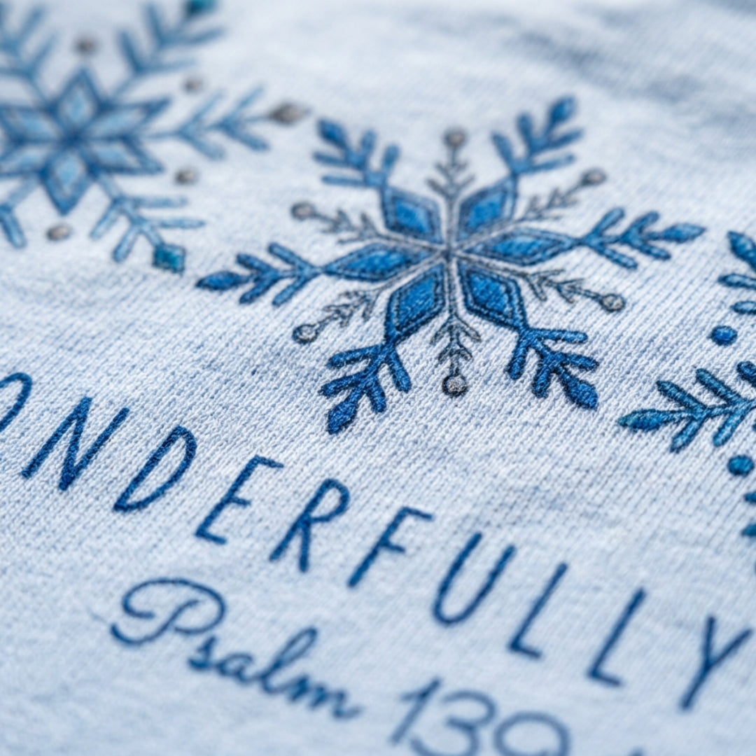 Close-up of a light blue fabric with embroidered blue snowflakes and the words 'WONDERFULLY Psalm 139' in blue thread.