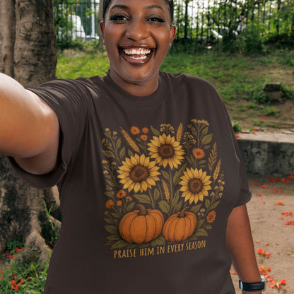 Person wearing a t-shirt with sunflower and pumpkin design that says Praise him in every season
