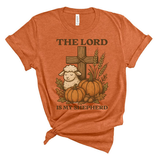 Orange t-shirt with a cross, sheep, pumpkins, and leaves design on a white background and text that says The Lord is my Shepherd