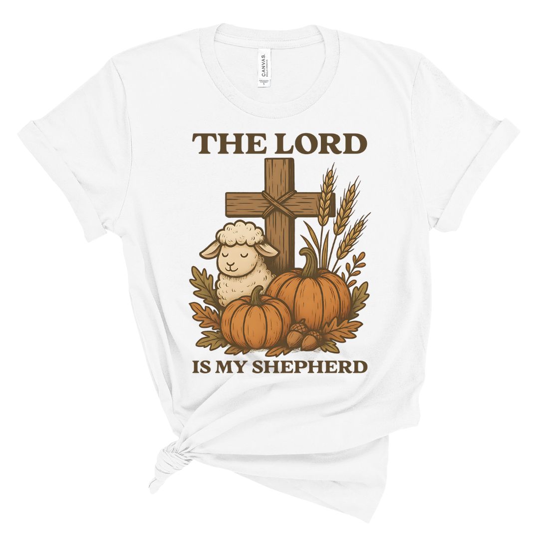 White t-shirt with a graphic of a cross, sheep, pumpkins, and wheat with 'The Lord is my Shepherd' text on a white background.