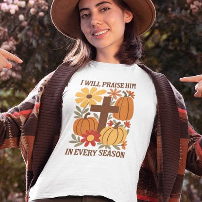 Person wearing a white t-shirt with a religious design featuring pumpkins and flowers, outdoors.