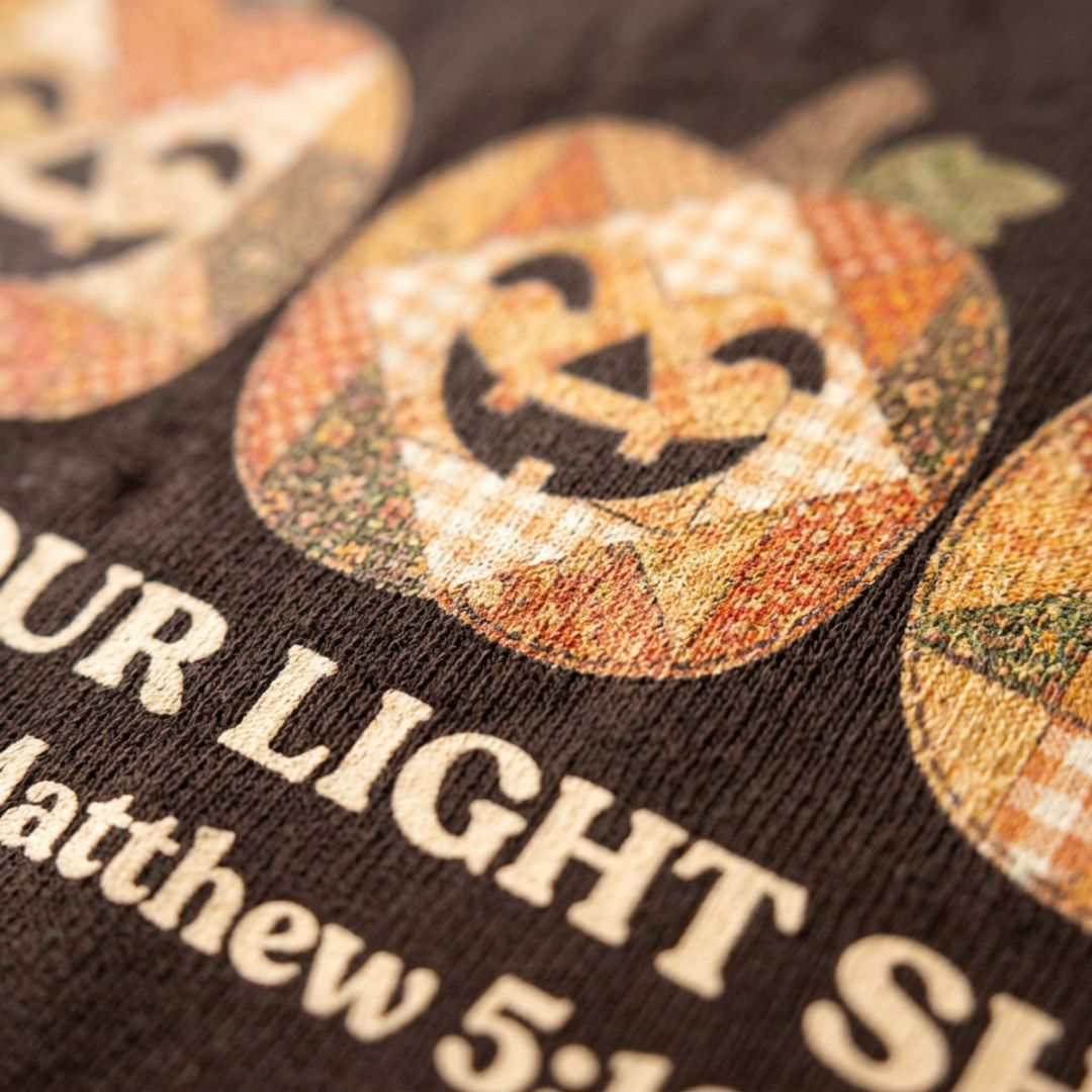 Christian shirt for women with three faux applique patchwork style pumpkins and “Let Your Light Shine, Matthew 5:16.” Printed design, not real fabric applique.