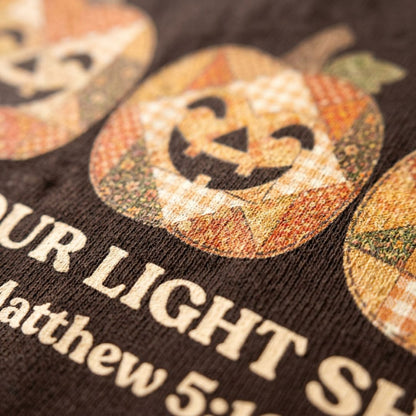Christian shirt for women with three faux applique patchwork style pumpkins and “Let Your Light Shine, Matthew 5:16.” Printed design, not real fabric applique.