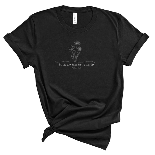 Christian t shirt for women featuring Psalm 46 10 Be still and know that I am God with delicate wildflower line art design, minimalist faith based graphic tee for everyday wear