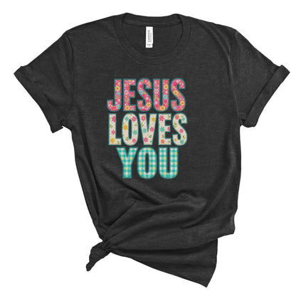 Christian t shirt featuring the phrase Jesus Loves You in colorful floral and gingham patterned letters. Printed faux embroidery and faux quilted patchwork graphic design with a vintage handmade look.
