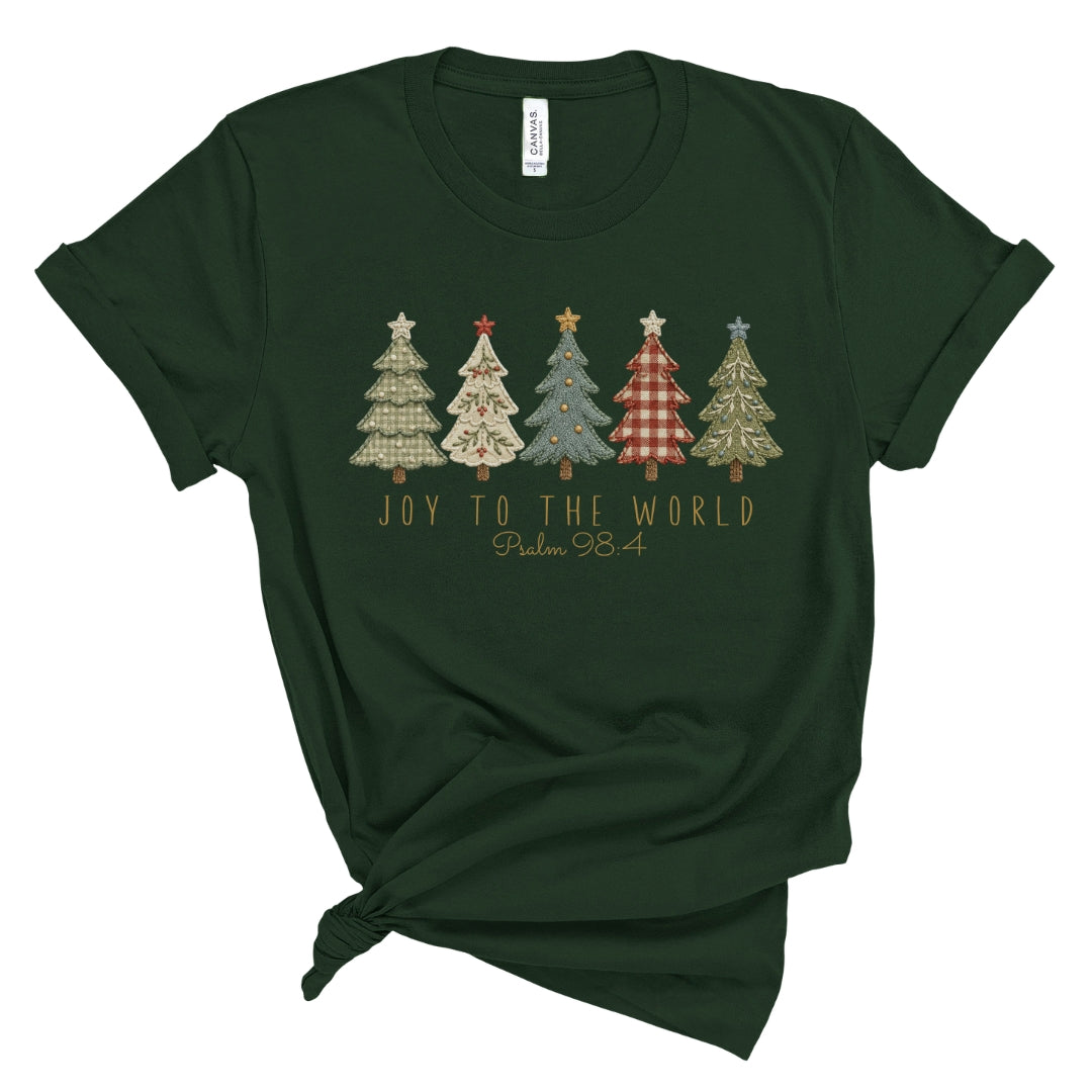 A dark forest green short-sleeve t-shirt with a knotted hem, featuring a graphic of five patterned Christmas trees and the text 'JOY TO THE WORLD Psalm 98' printed on the chest.