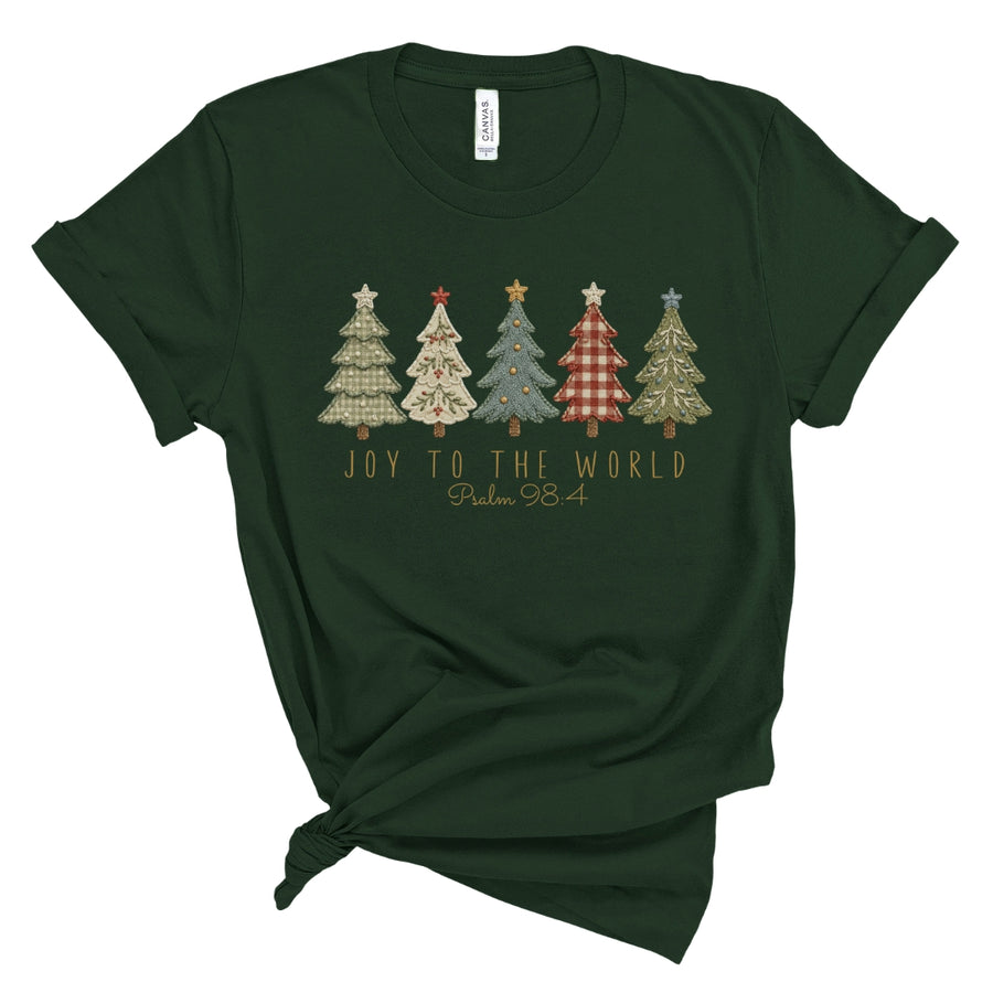 A dark forest green short-sleeve t-shirt with a knotted hem, featuring a graphic of five patterned Christmas trees and the text 'JOY TO THE WORLD Psalm 98' printed on the chest.