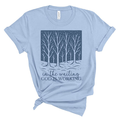 Christian t-shirt for women with a graphic of  winter trees and text 'In the waiting God is working' on a white background