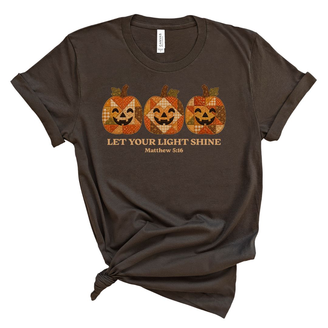 Christian shirt for women with three faux applique patchwork style pumpkins and “Let Your Light Shine, Matthew 5:16.” Printed design, not real fabric applique.