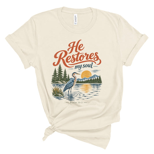 Christian T shirt with “He Restores My Soul,” Psalm 23:3, and a vintage heron, lake, mountain, evergreen, and sunset design.
