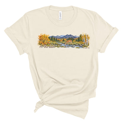 shirt with a wide watercolor style mountain landscape, golden trees, a deer drinking from a rocky creek, and “As the deer” and “Psalm 42.”