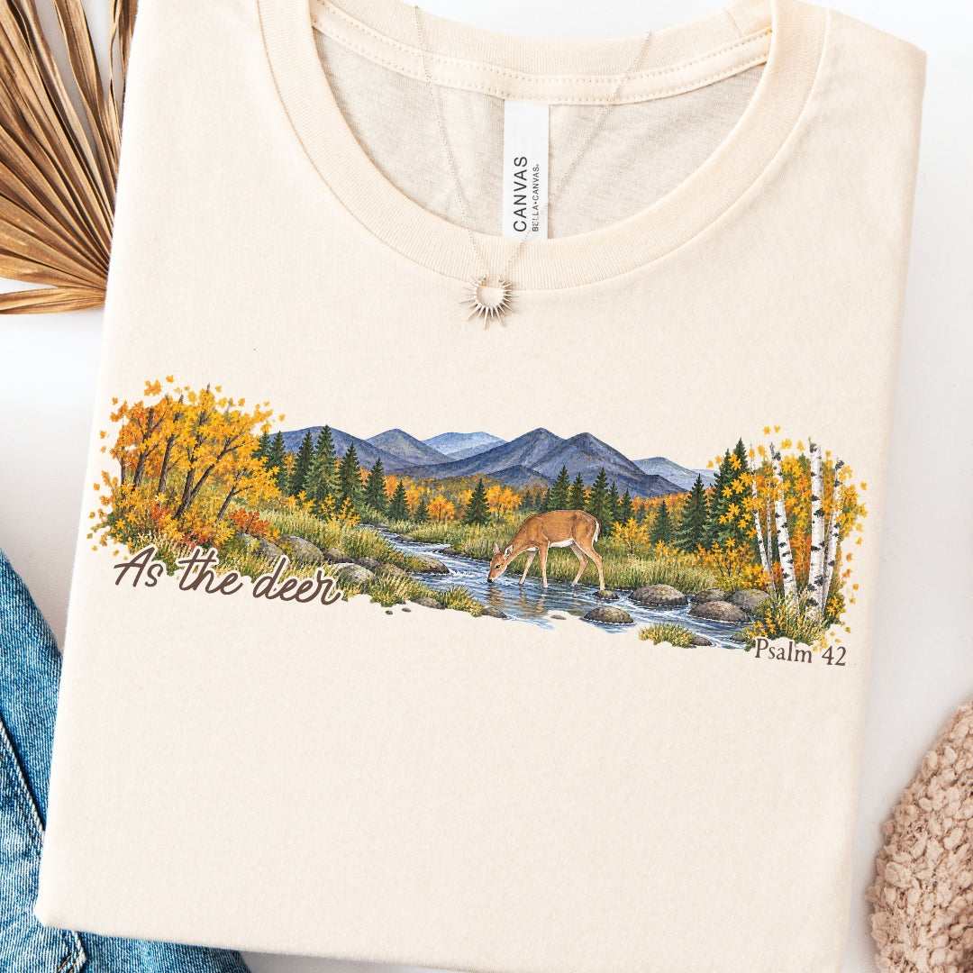 shirt with a wide watercolor style mountain landscape, golden trees, a deer drinking from a rocky creek, and “As the deer” and “Psalm 42.”
