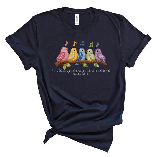 Christian t shirt featuring colorful faux embroidery quilt style birds singing on a branch with the Bible verse I will sing of the goodness of God, Psalm 89:1.