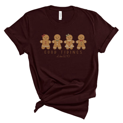 Christian Christmas tee with four gingerbread characters in a printed faux embroidery style, with Good Tidings and Luke 2:10 underneath.