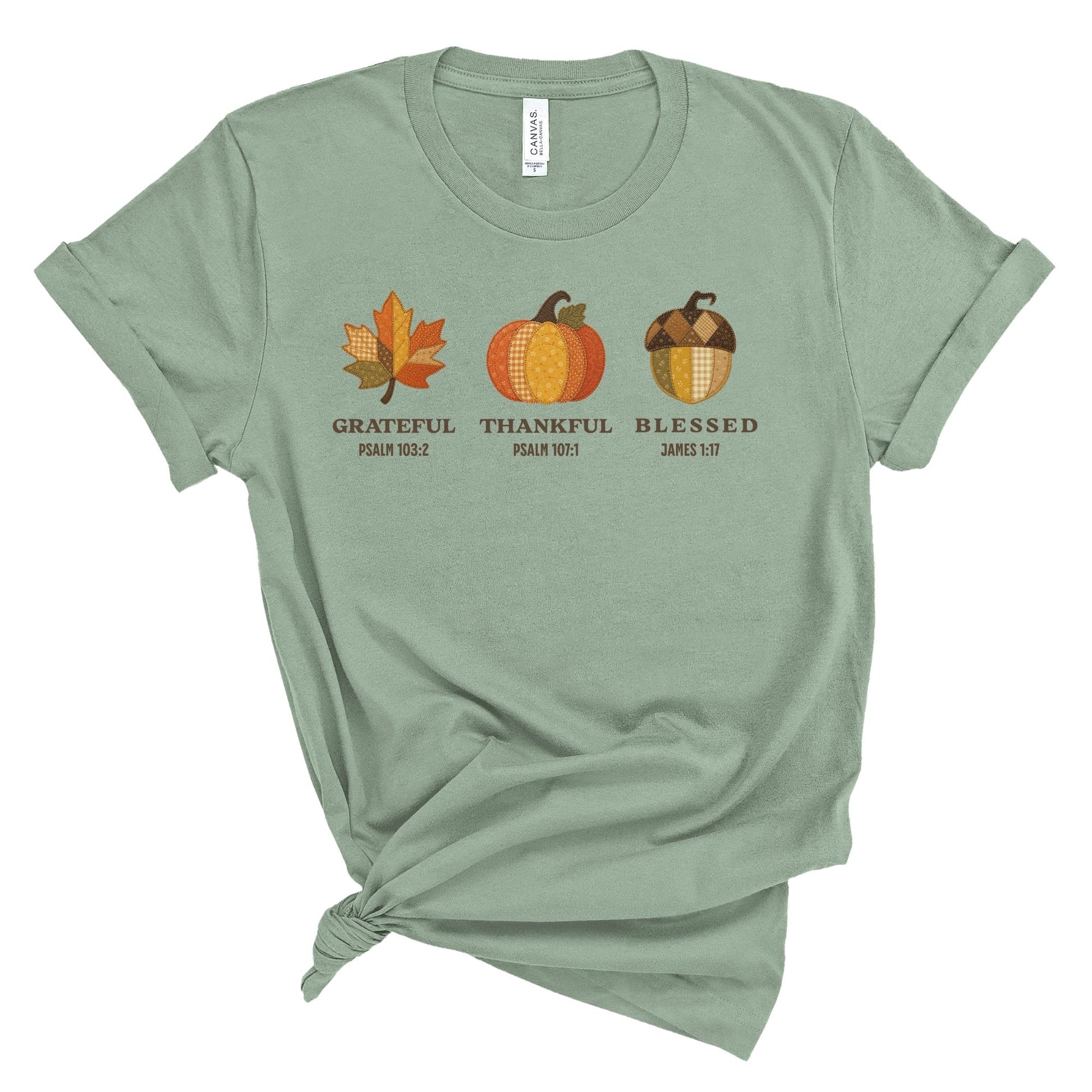 Cream Christian t shirt for women featuring patchwork style fall leaf, pumpkin, and acorn with the words Grateful, Thankful, Blessed and Bible verses Psalm 103:2, Psalm 107:1, and James 1:17.