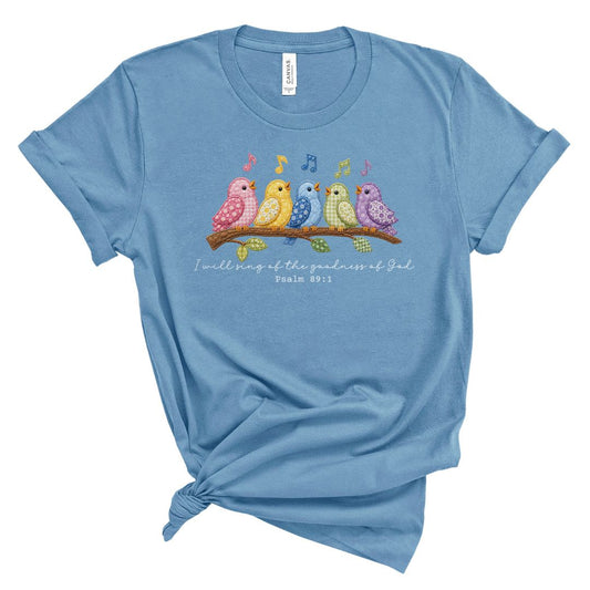 Christian t shirt featuring colorful faux embroidery quilt style birds singing on a branch with the Bible verse I will sing of the goodness of God, Psalm 89:1.