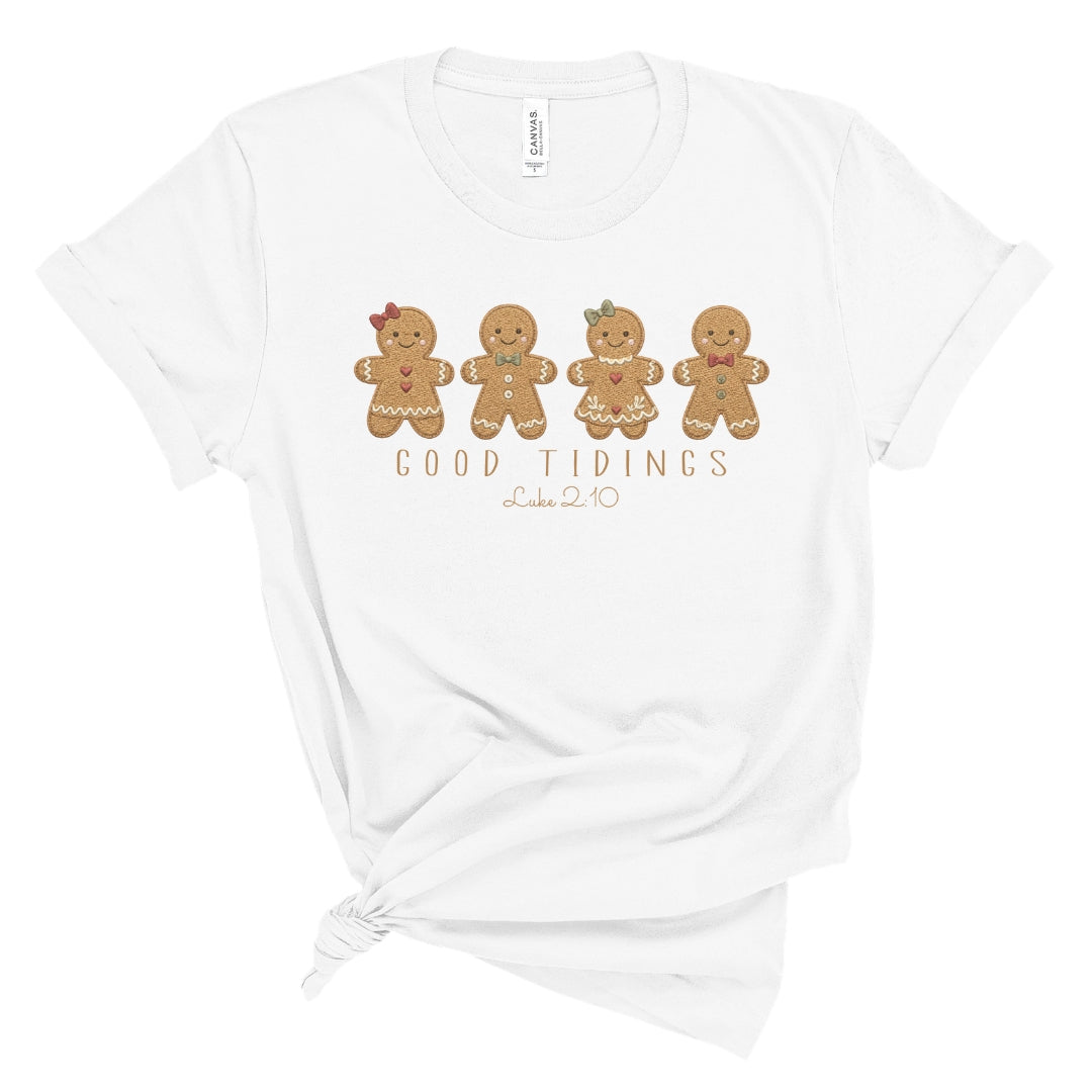 Christian Christmas tee with four gingerbread characters in a printed faux embroidery style, with Good Tidings and Luke 2:10 underneath.