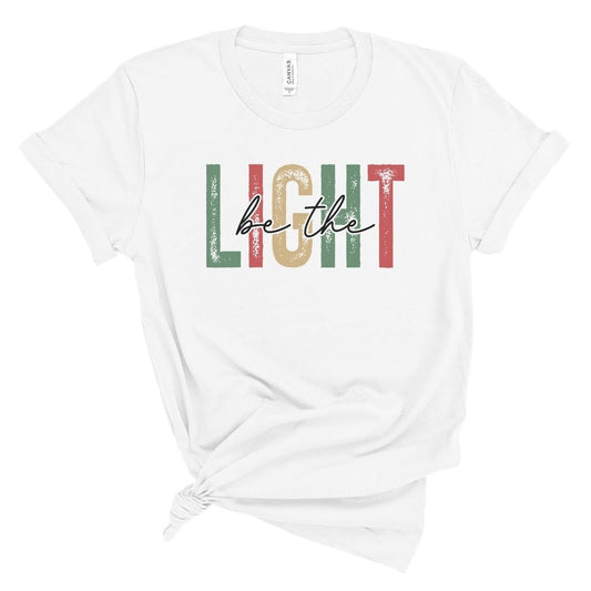 White t-shirt with 'be the light' text in colorful letters on a white background