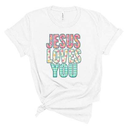 Christian t shirt featuring the phrase Jesus Loves You in colorful floral and gingham patterned letters. Printed faux embroidery and faux quilted patchwork graphic design with a vintage handmade look.