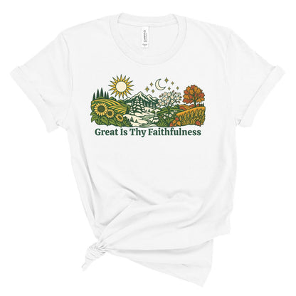 A white short-sleeve t-shirt with a graphic of a scenic landscape and the text 'Great Is Thy Faithfulness' printed on the front, styled with a knot at the bottom hem.